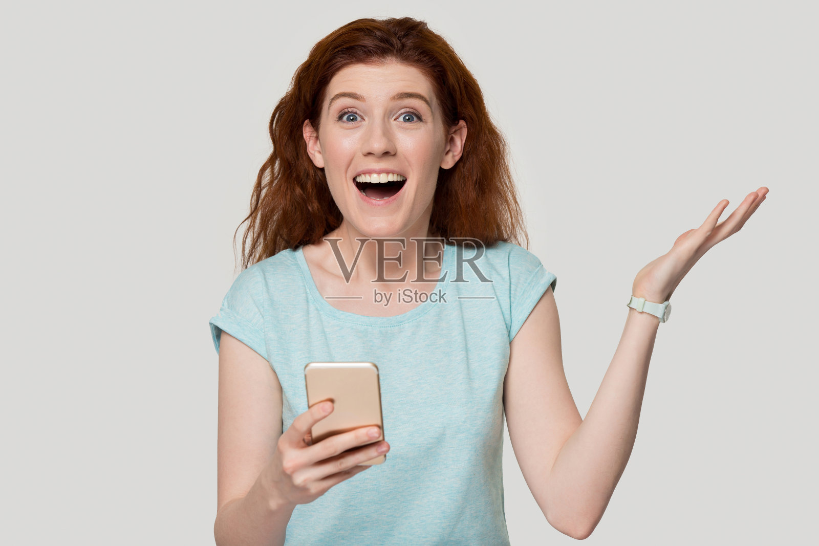 快乐的红发年轻女子收到令人难以置信的优惠短信。照片摄影图片