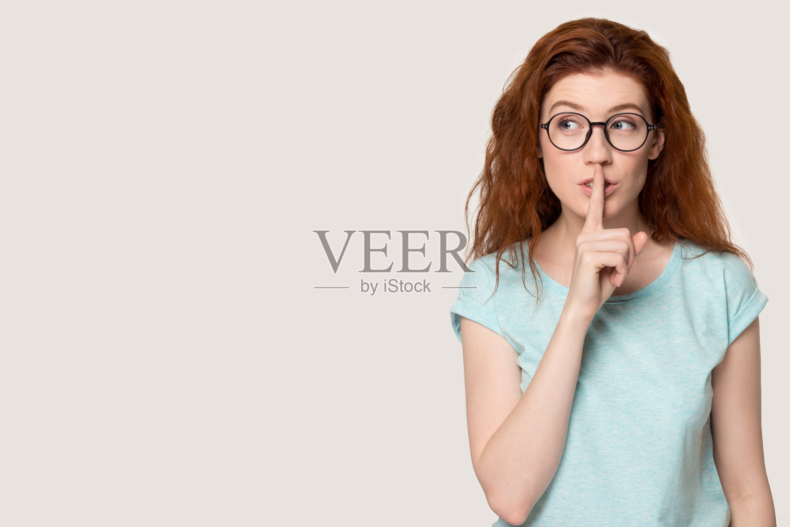 年轻的红头发女人做着安静的手势。照片摄影图片