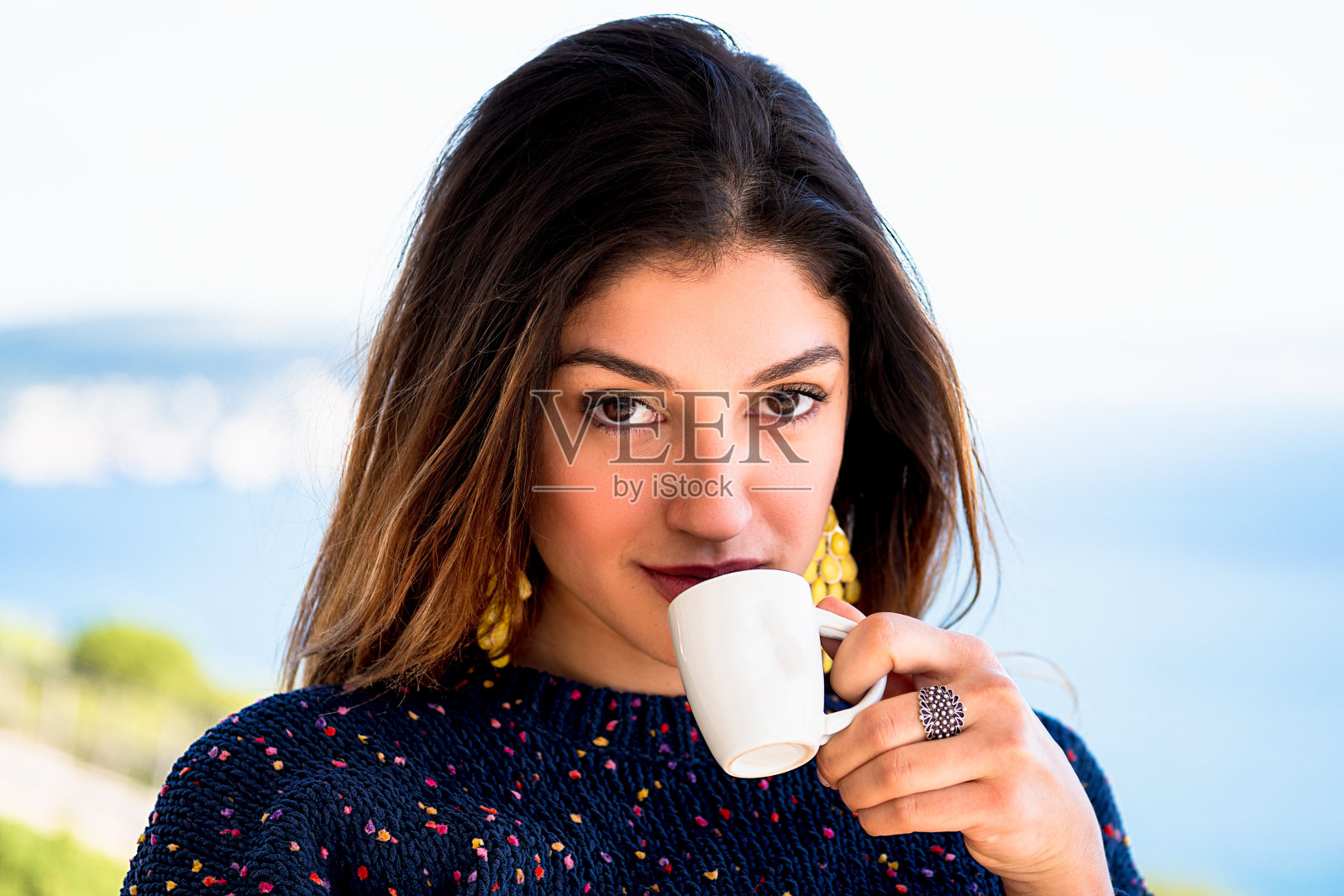 一个漂亮的女孩手里拿着一杯咖啡，正在享受着一杯好咖啡。前景照片与蓝色背景理想的健康和饮食照片摄影图片