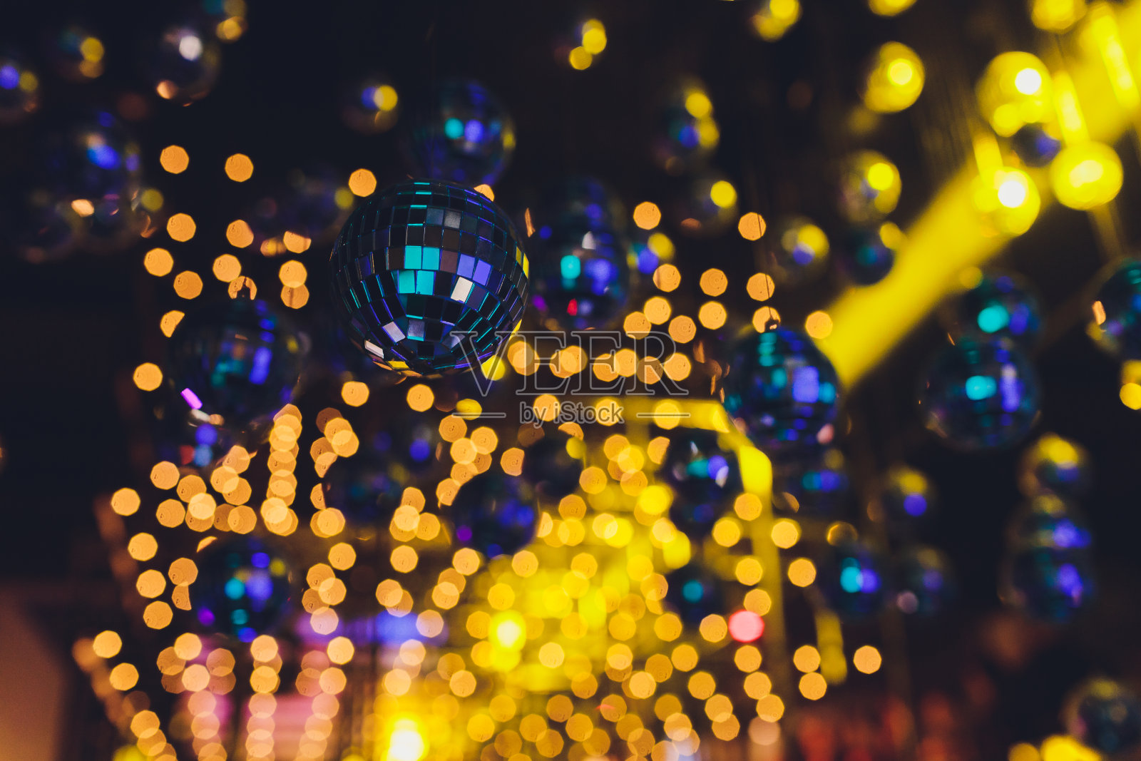 许多镜子迪斯科球悬挂与彩色灯光反射。照片摄影图片