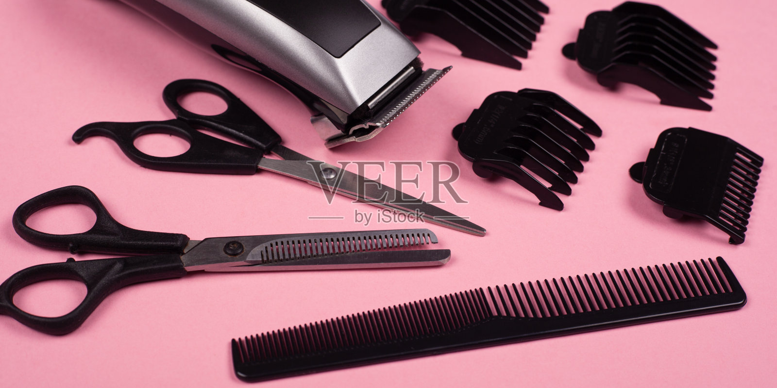 粉色背景上的理发工具，理发器，直剪和薄剪和梳子照片摄影图片