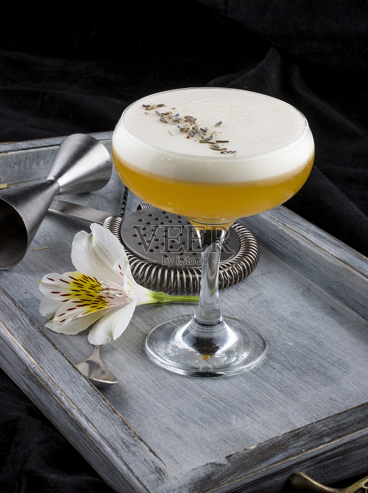精致的鸡尾酒装在玻璃杯里，放在木板上。黑暗的背景。酒保配件。照片摄影图片