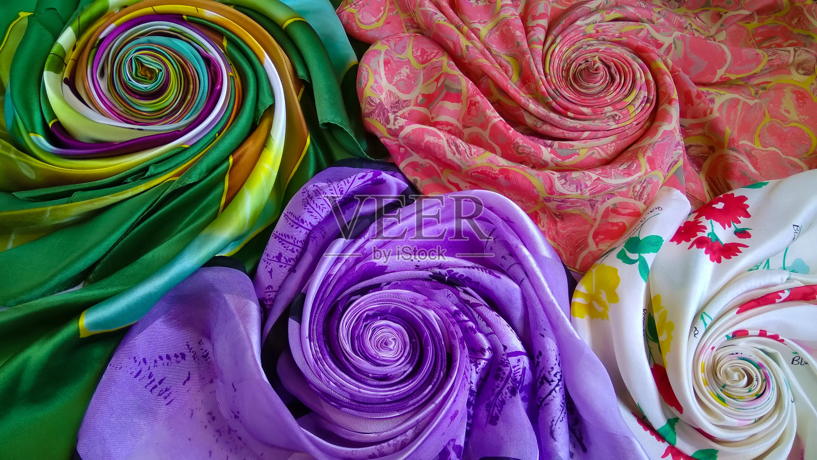 各种各样美丽的丝绸织物卷成玫瑰的形式照片摄影图片