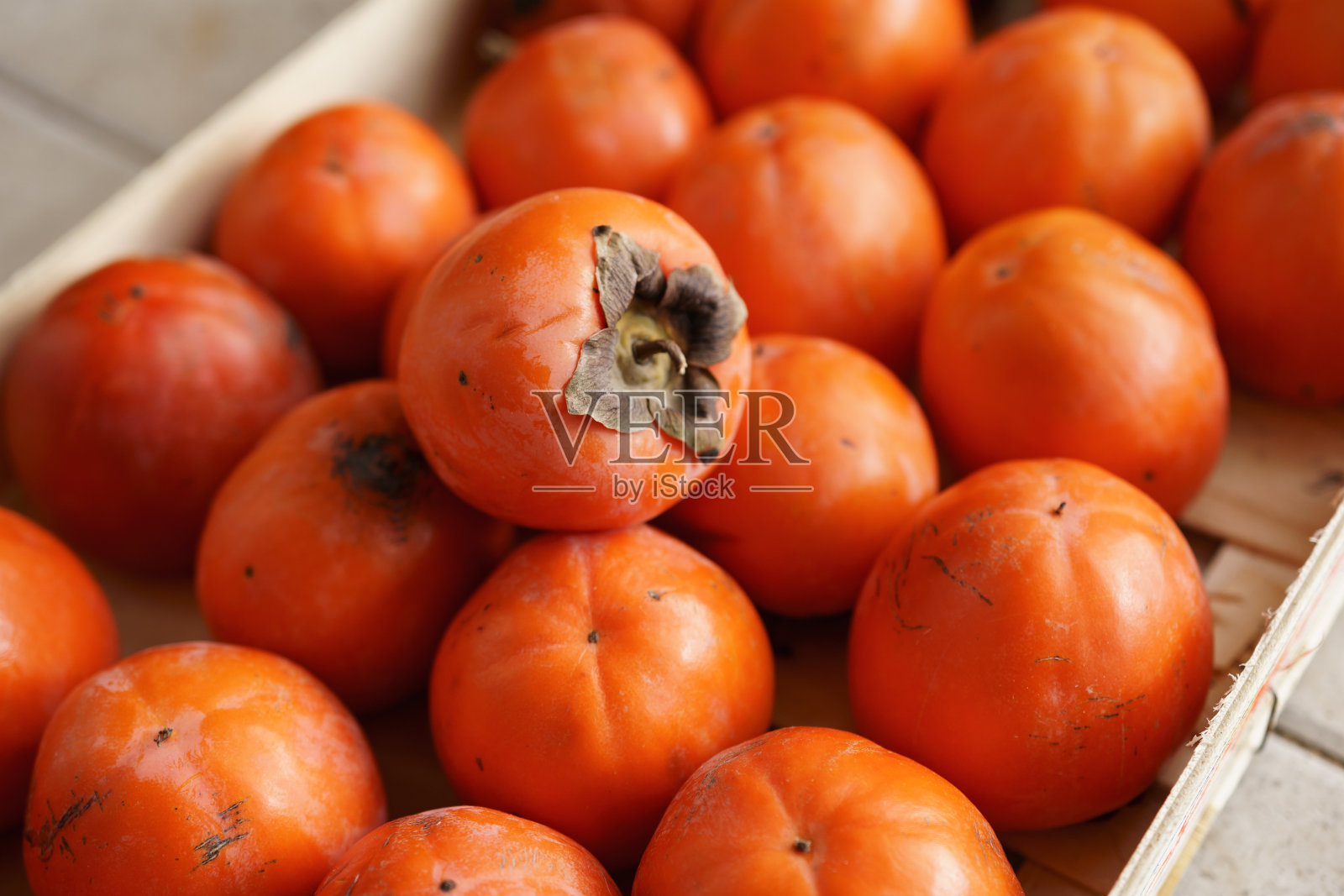 抽屉里有熟了的橙柿子。质地的背景是柿子。照片摄影图片