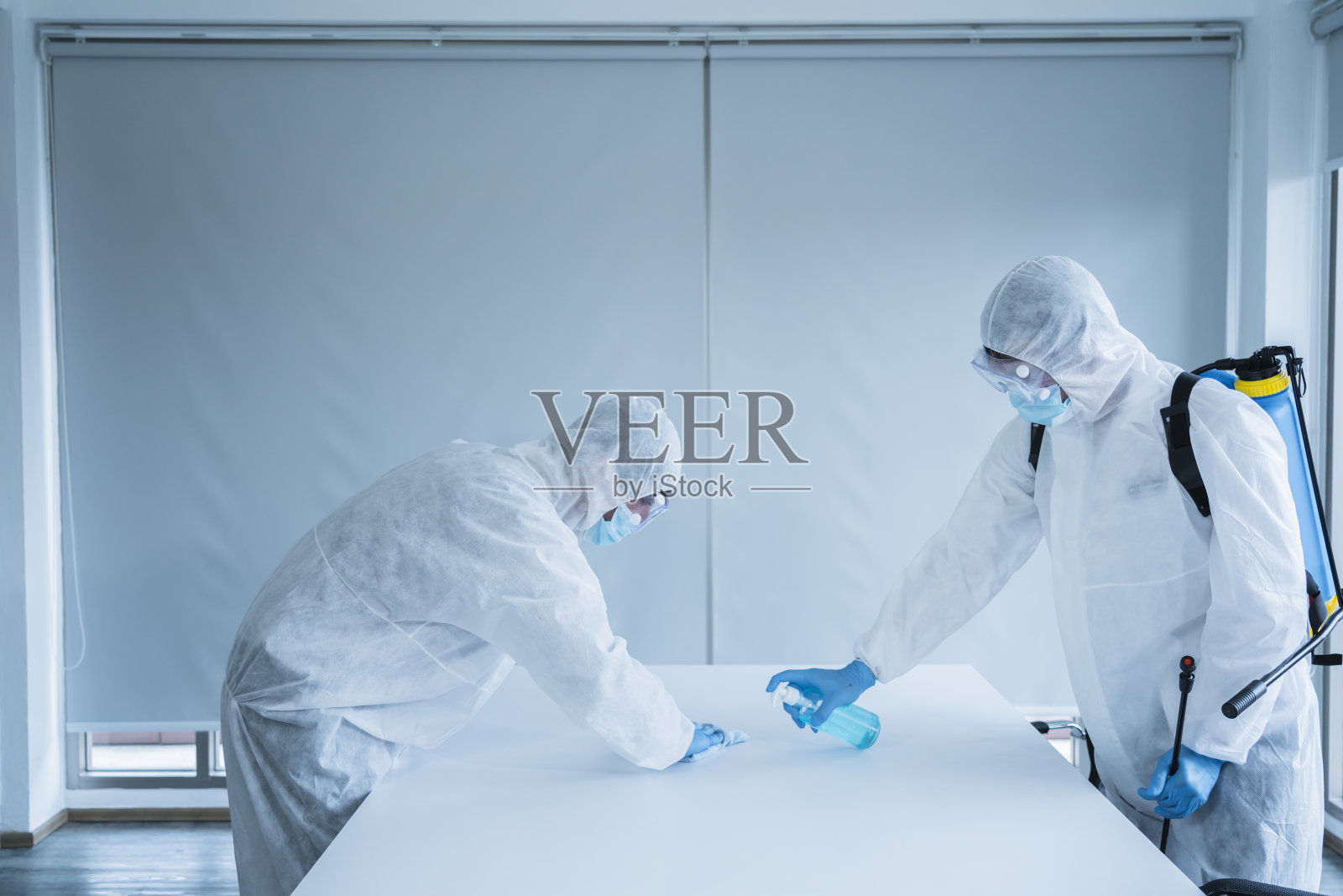 穿着病毒防护服和口罩的人用布擦拭和清洁新冠肺炎感染区照片摄影图片