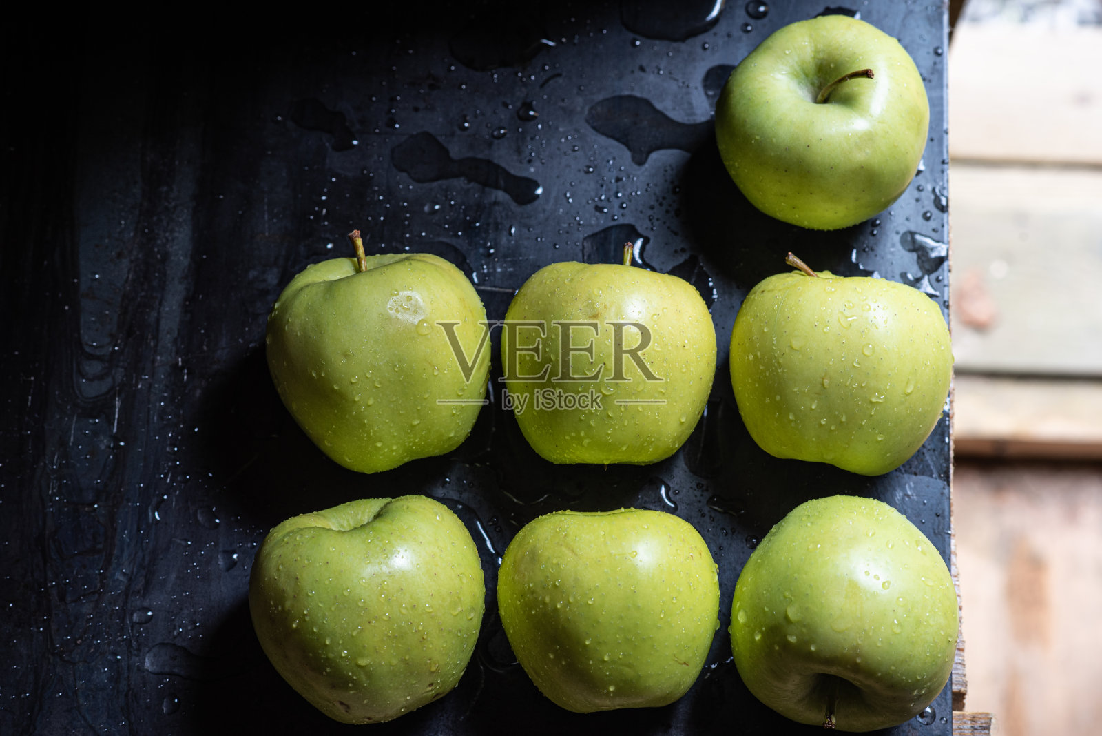 绿色的苹果水滴在黑色金属板上，背景是绿色的草照片摄影图片