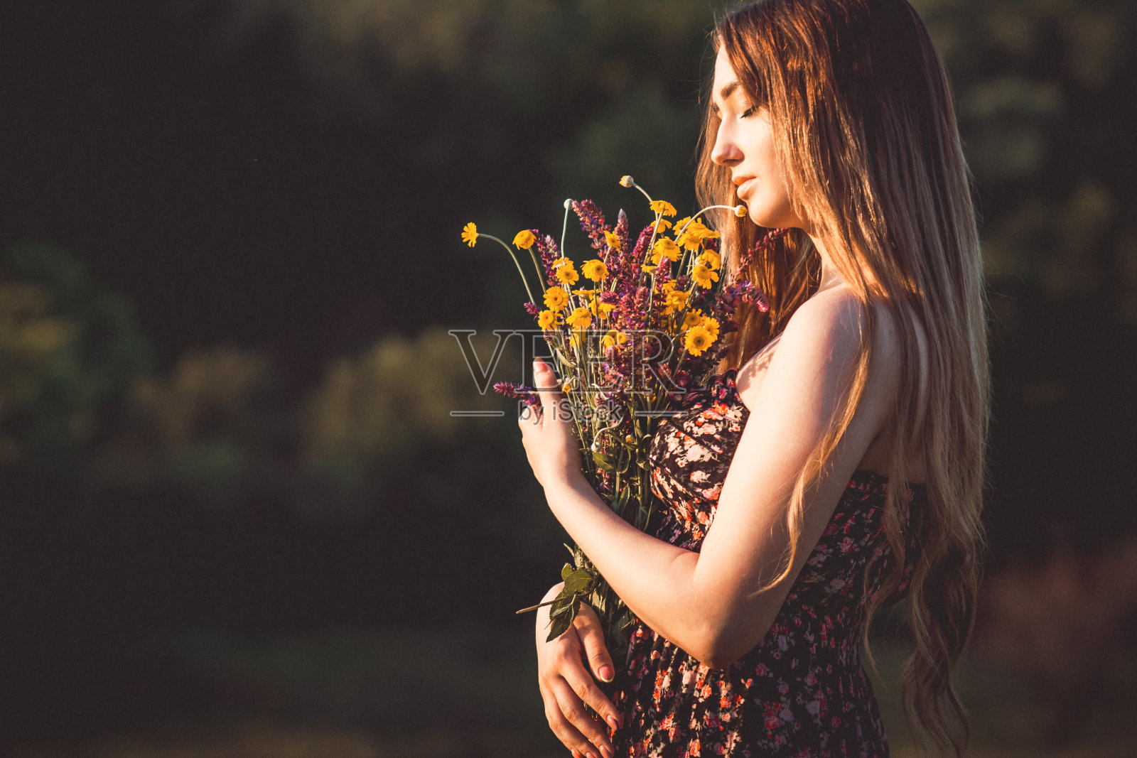 美丽的女孩与野花在草地上，年轻的女人长头发穿着衣服走在自然，夏天温柔的照片在村庄照片摄影图片