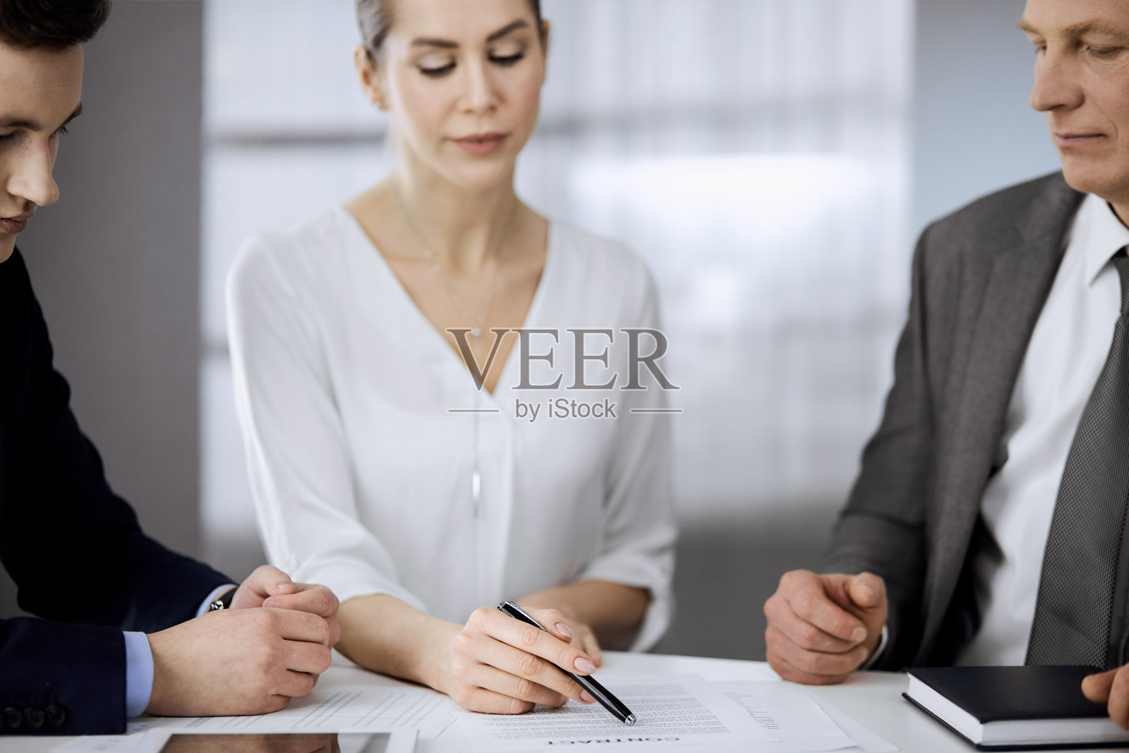 一位年长的商人和一群商人在办公室讨论合同。女人和律师一起开会。团队精神和合作照片摄影图片