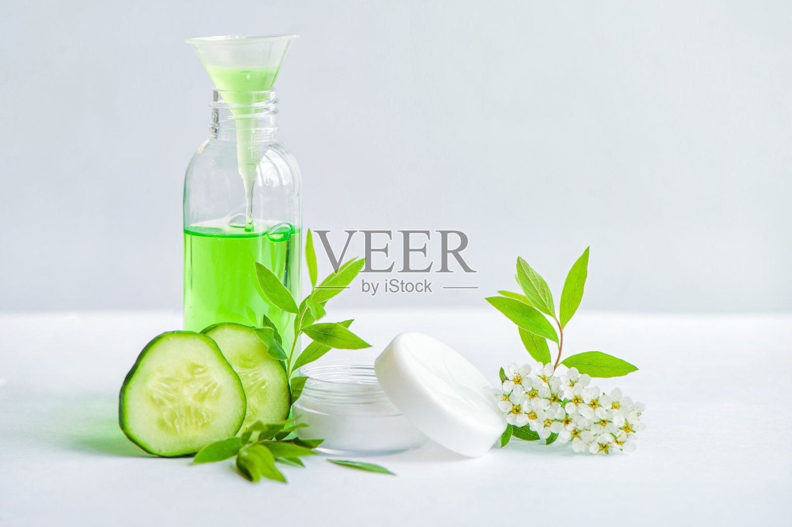 玻璃瓶里的面霜，新鲜黄瓜片，白色背景的绿色清爽凝胶。新鲜的叶子。水疗。照片摄影图片