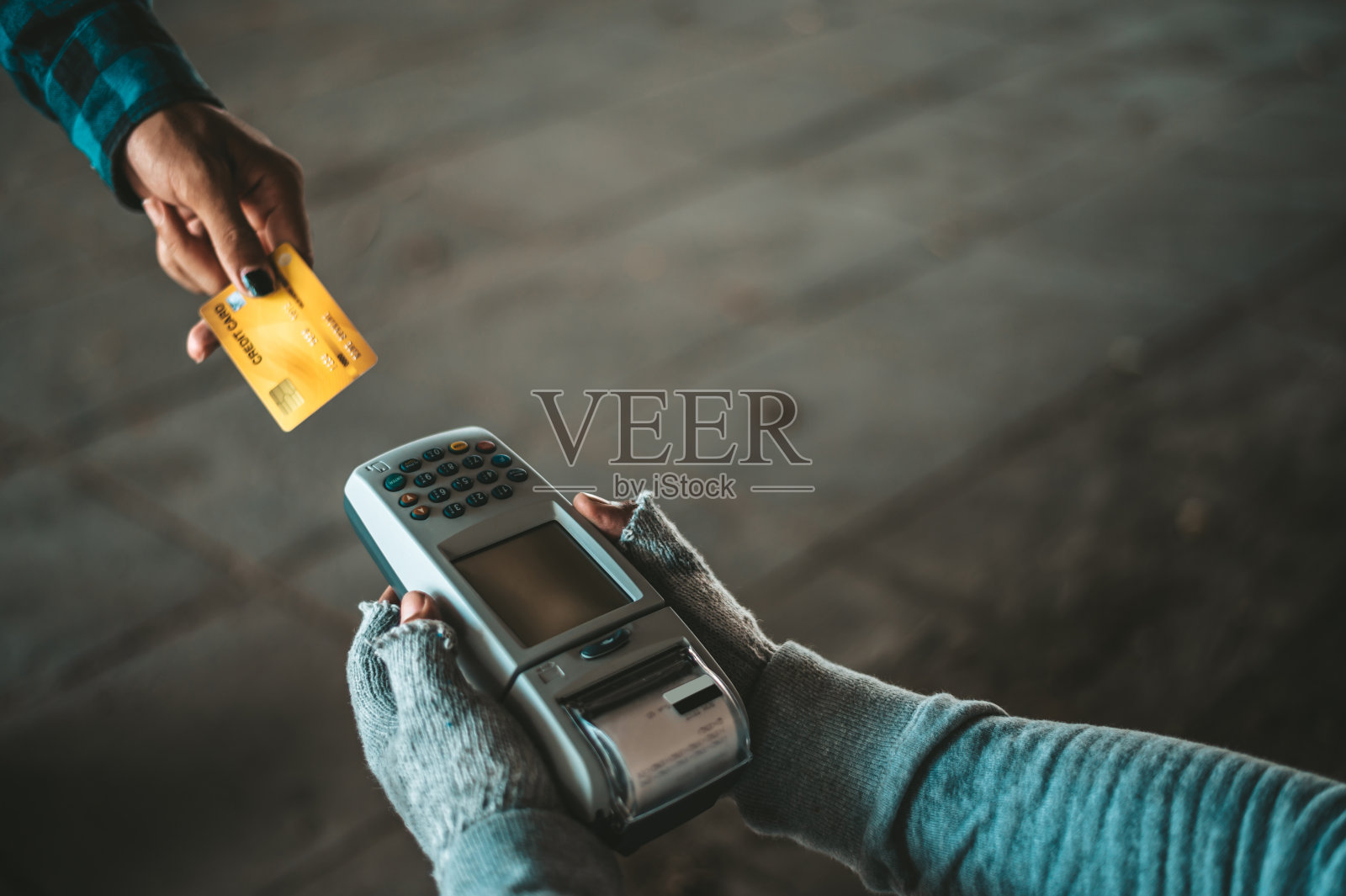 坐在天桥下的乞丐手里拿着信用卡和刷卡机。照片摄影图片