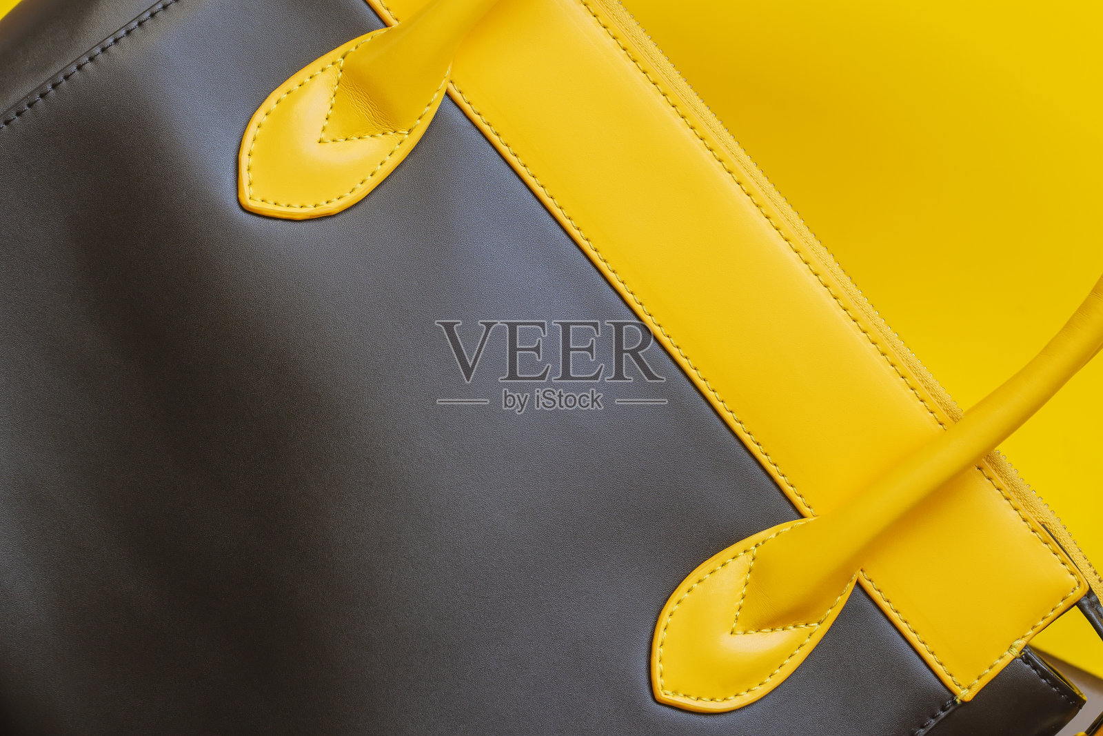 细节皮革手袋上的黄色背景，俯视图，平lay。没有名字，没有标识。购物的概念。照片摄影图片