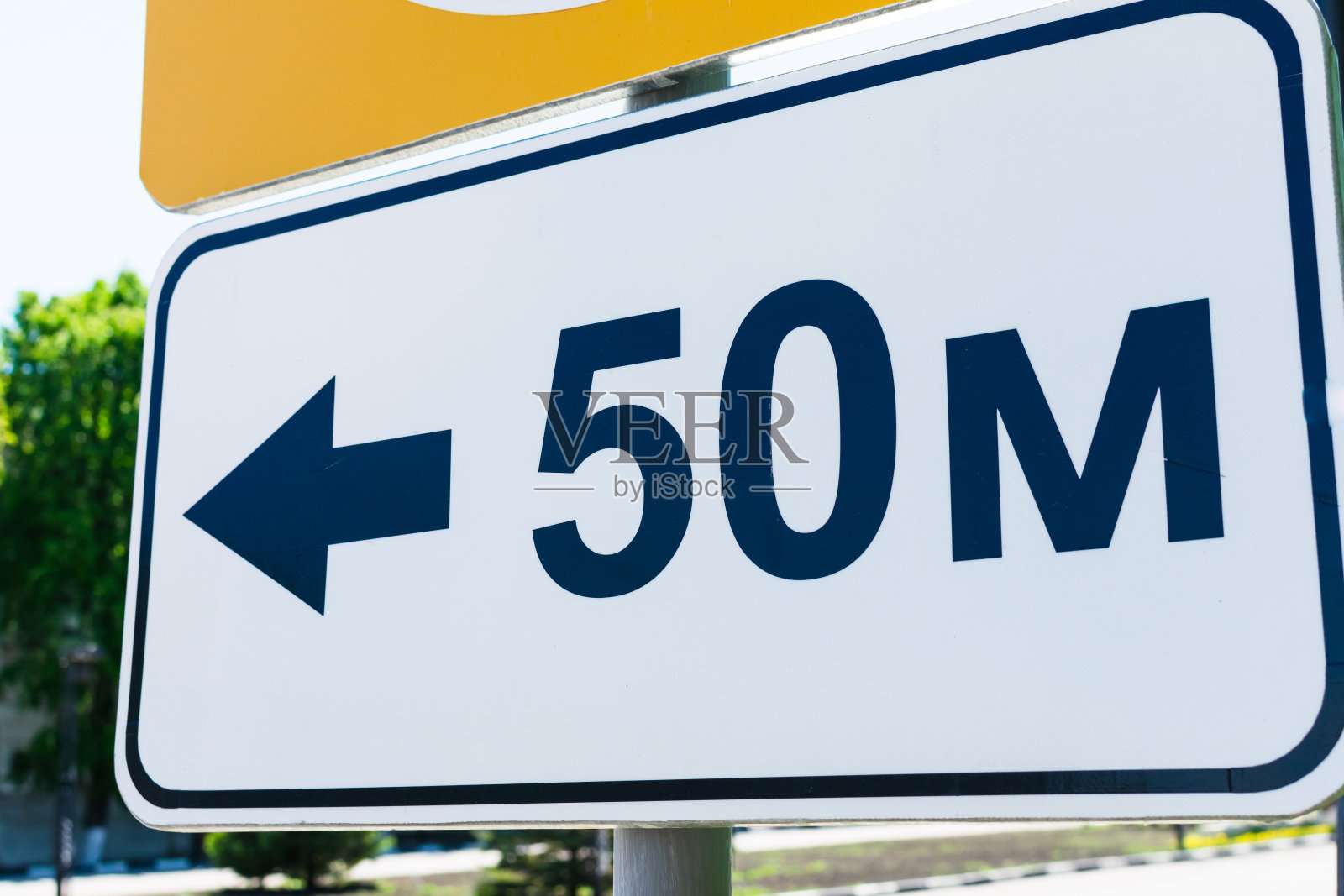 白色长方形路标，50米，有方向指示。照片摄影图片