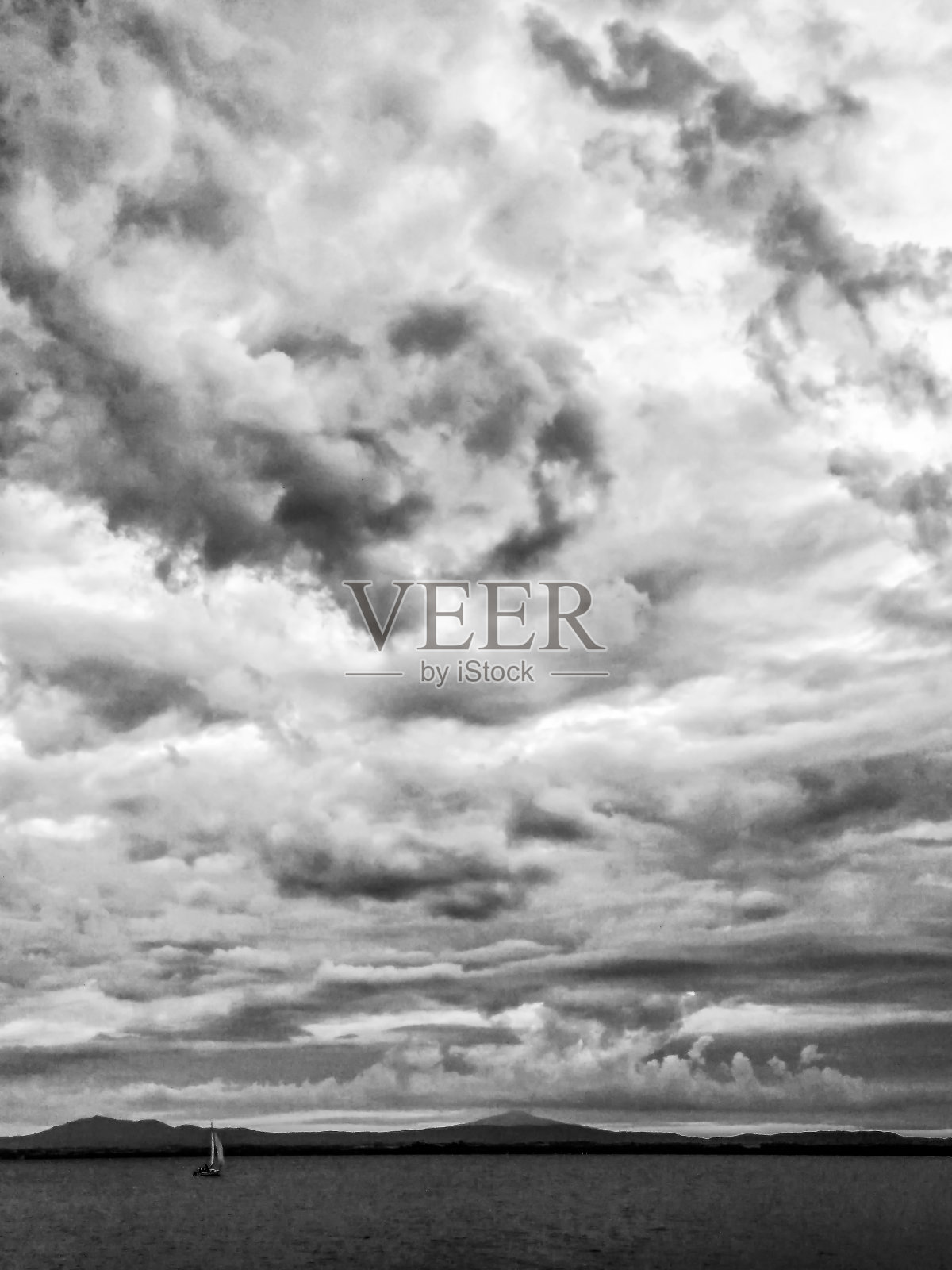 湖面上是一片阴沉沉的大天空，上面有一条小帆船照片摄影图片