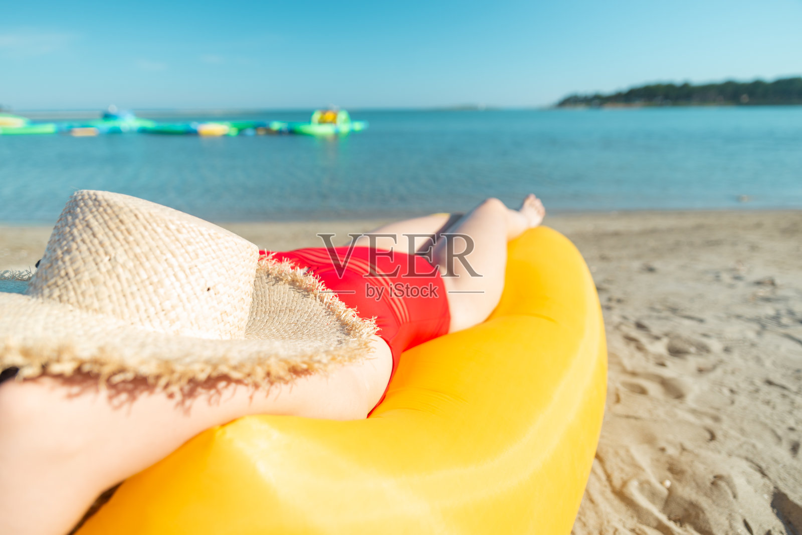 年轻漂亮的女人在红色的泳衣在黄色的空气沙发在夏天的海滩照片摄影图片