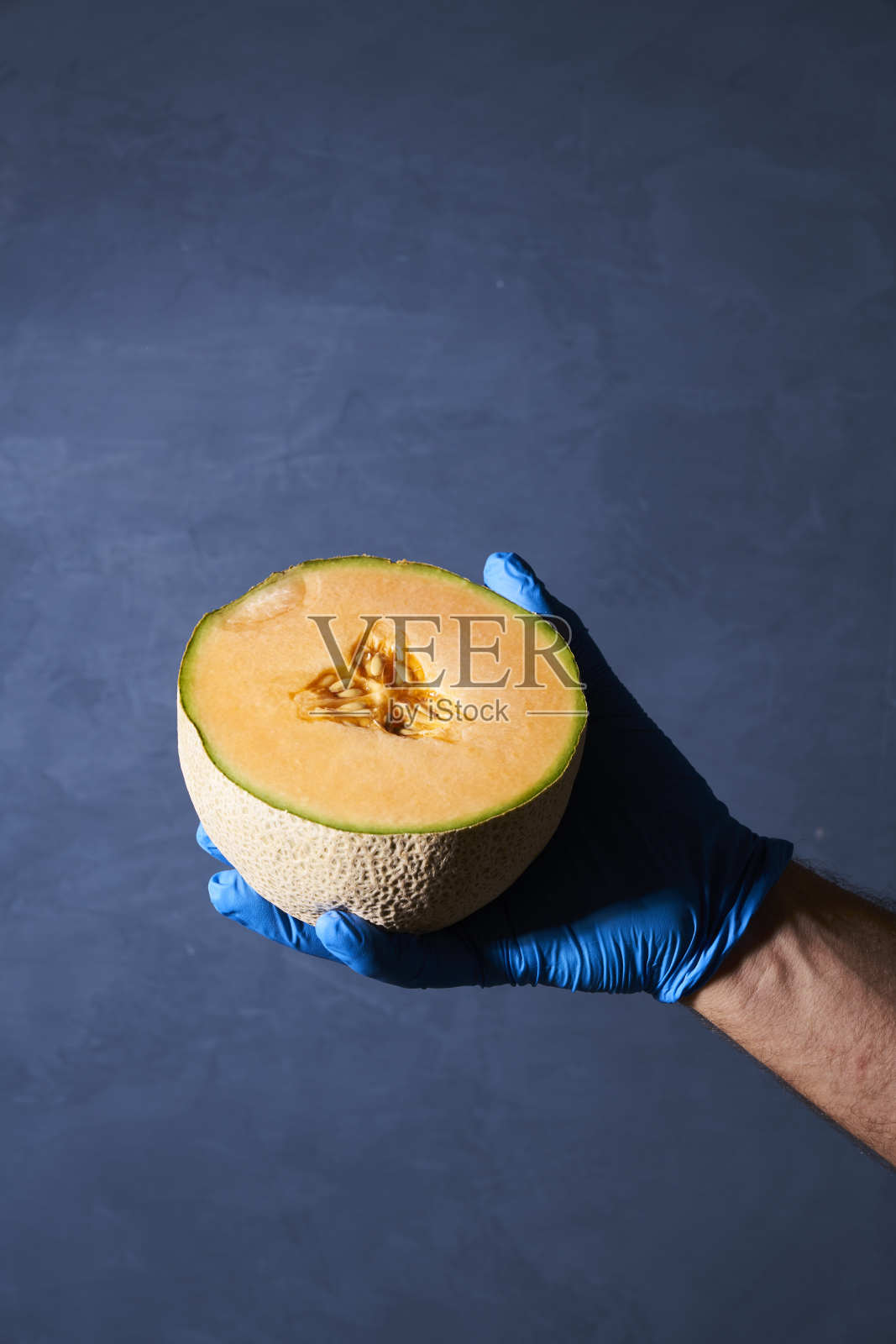 用戴手套的手拿哈密瓜食物照片摄影图片