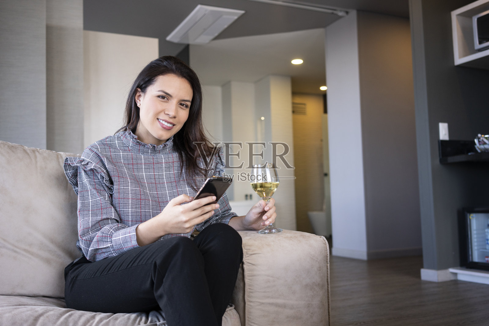 一名拉美裔女性在新冠肺炎期间饮酒并进行视频通话。照片摄影图片
