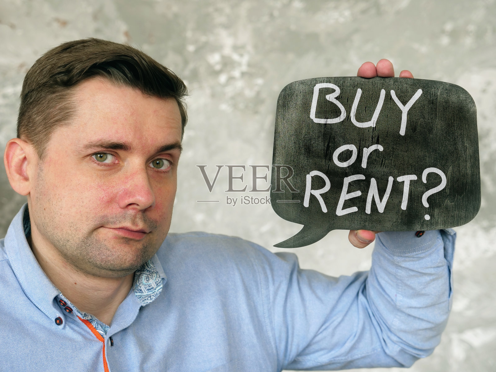 一个男人举着一个牌子，上面写着买还是租。照片摄影图片