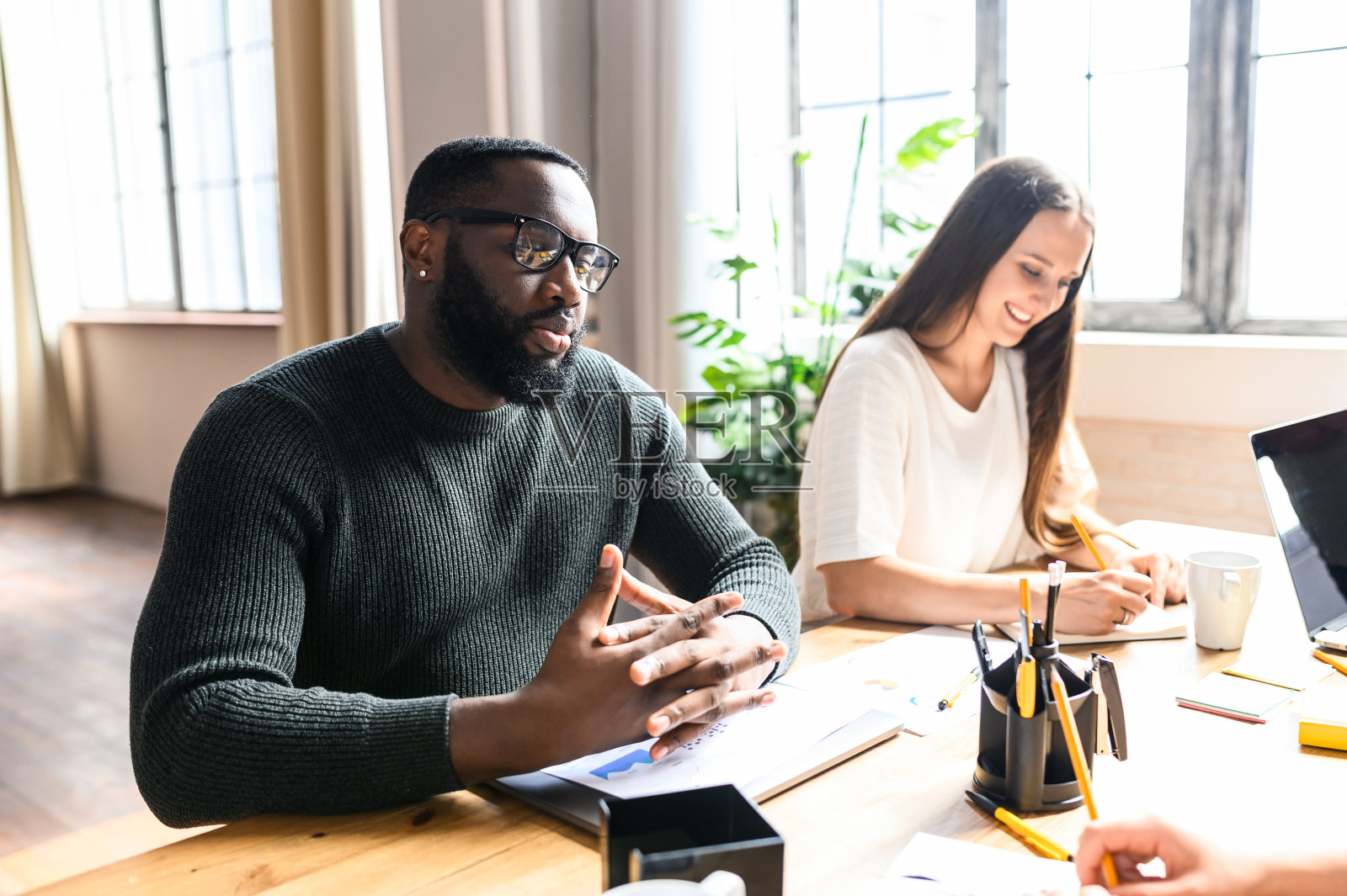 两个来自不同种族的同事坐在办公桌前照片摄影图片