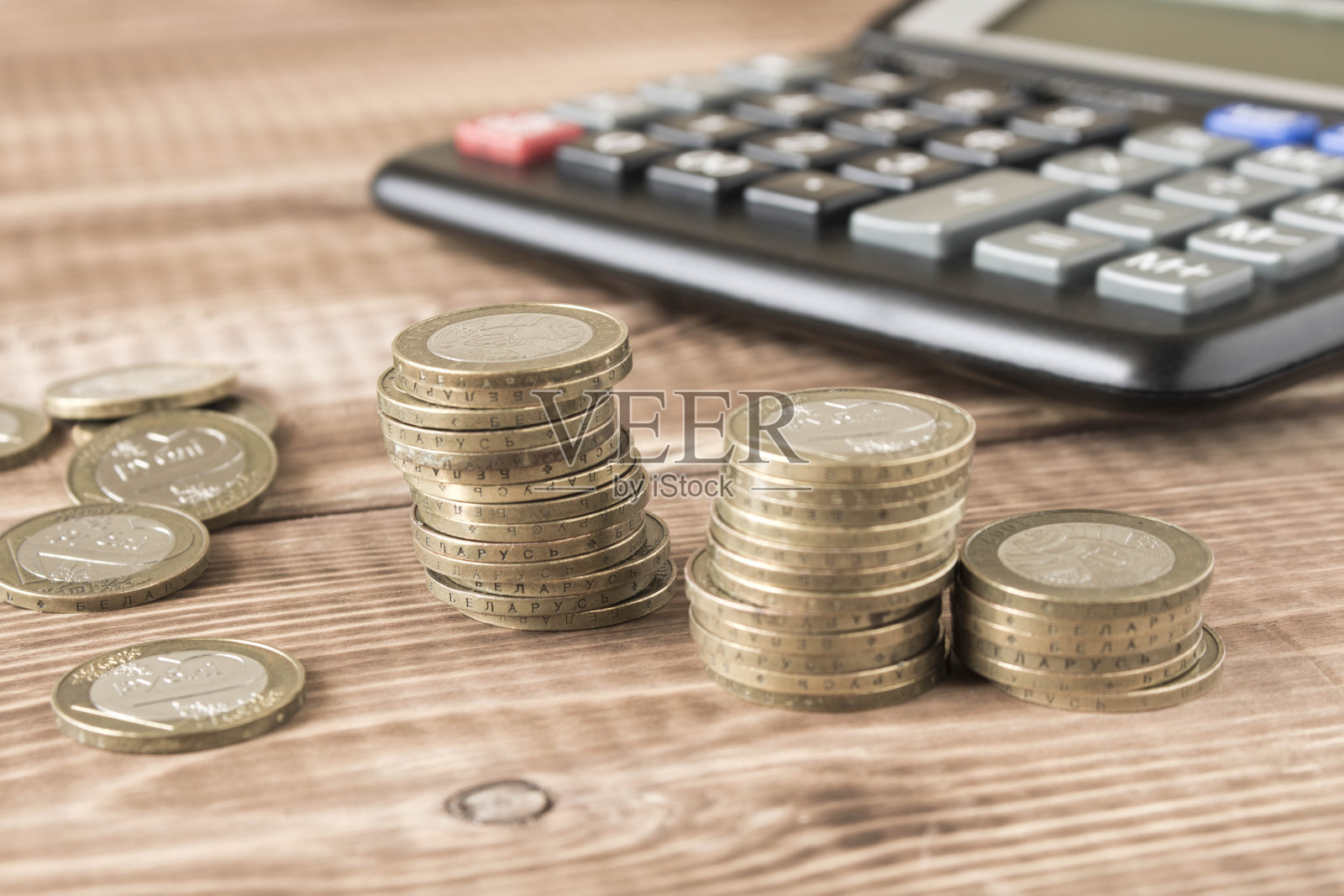 木桌上放着一堆硬币和一个计算器。储蓄和财务会计的概念。有选择性的重点。照片摄影图片