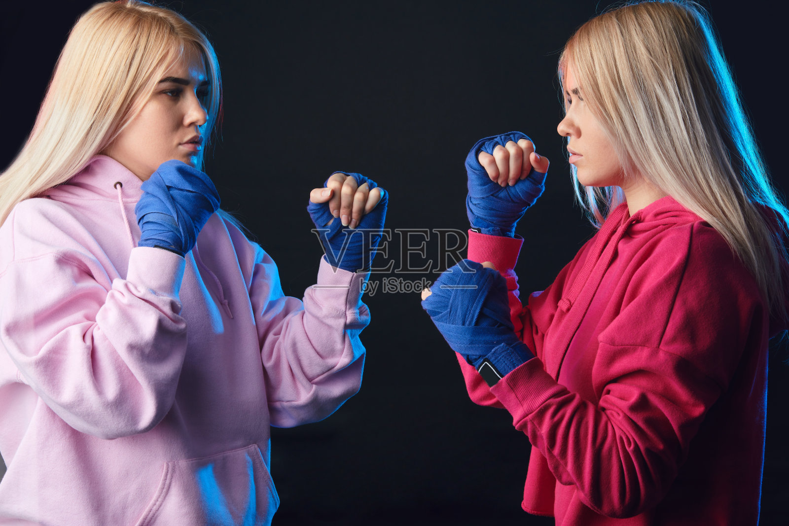 女拳击手拳击伙伴在一个拳击工作室的蓝色手包。照片摄影图片