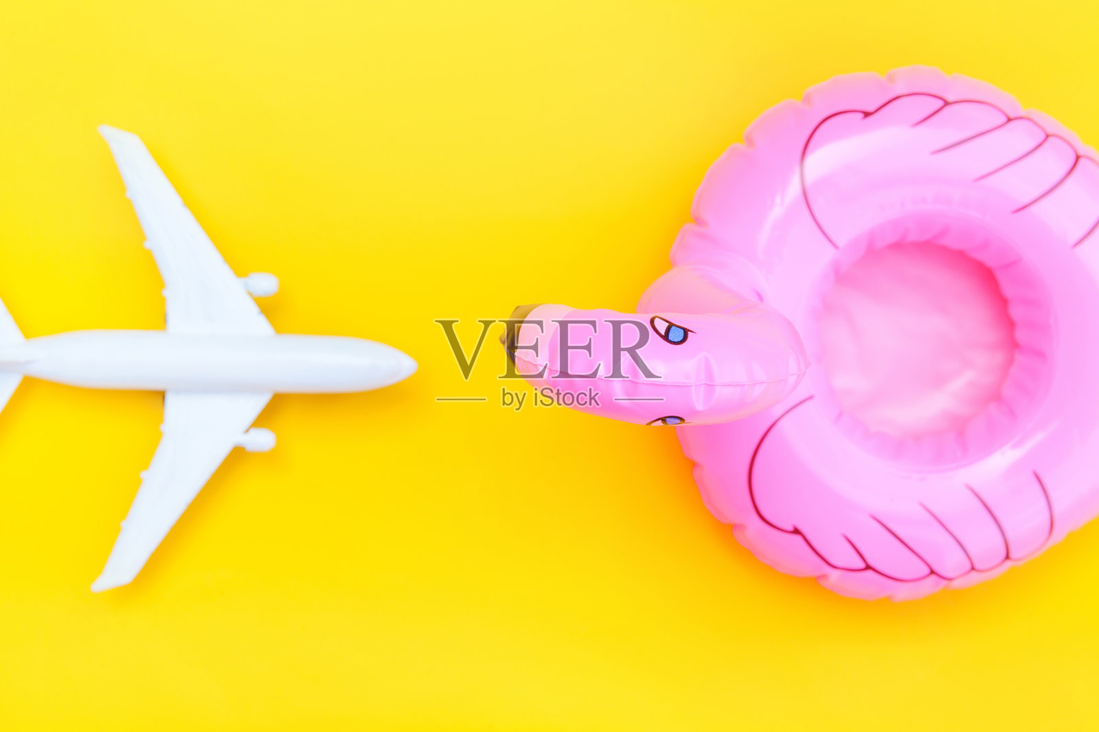 夏天海滩组成。用飞机和充气火烈鸟隔离在黄色的背景上。度假旅行冒险旅行概念。俯视图拷贝空间照片摄影图片