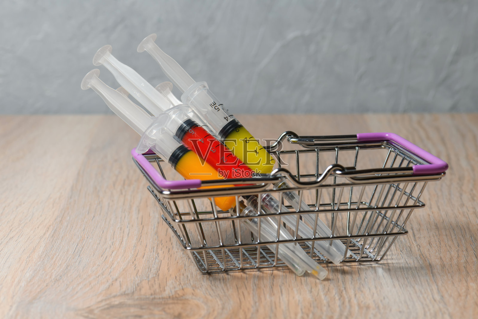 购买新冠病毒感染药物疫苗的概念。篮子里五颜六色的注射器。照片摄影图片