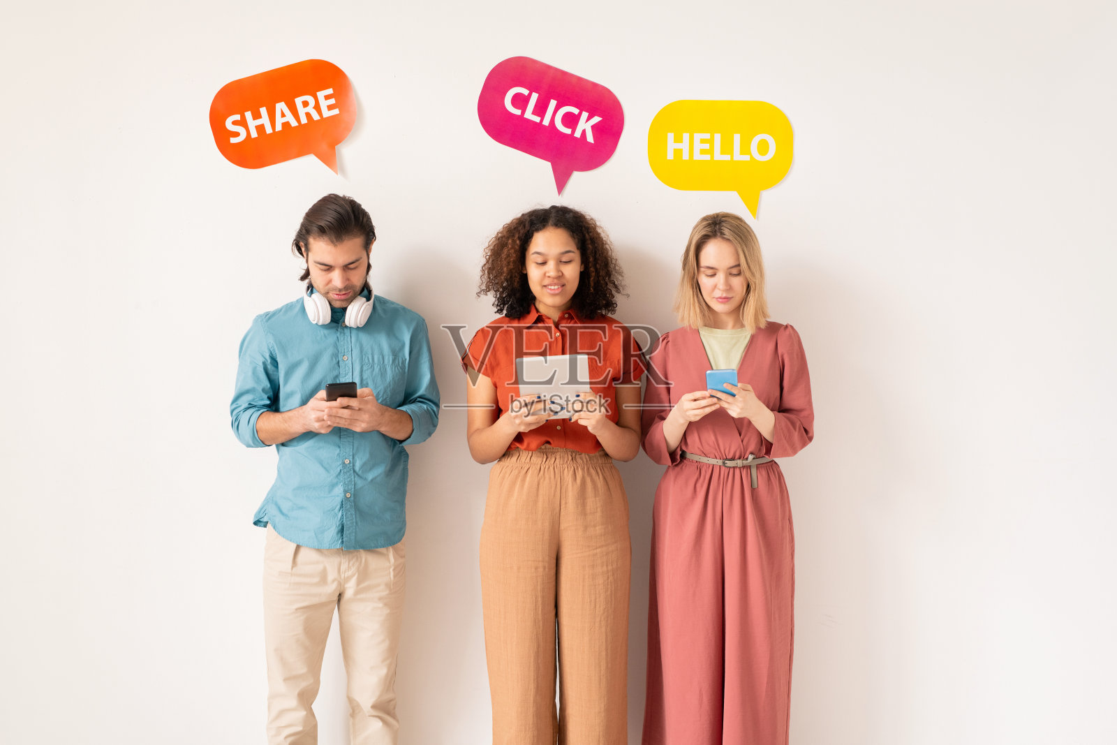 两个跨文化女孩和一个穿着休闲装的年轻人在移动设备上滚动照片摄影图片