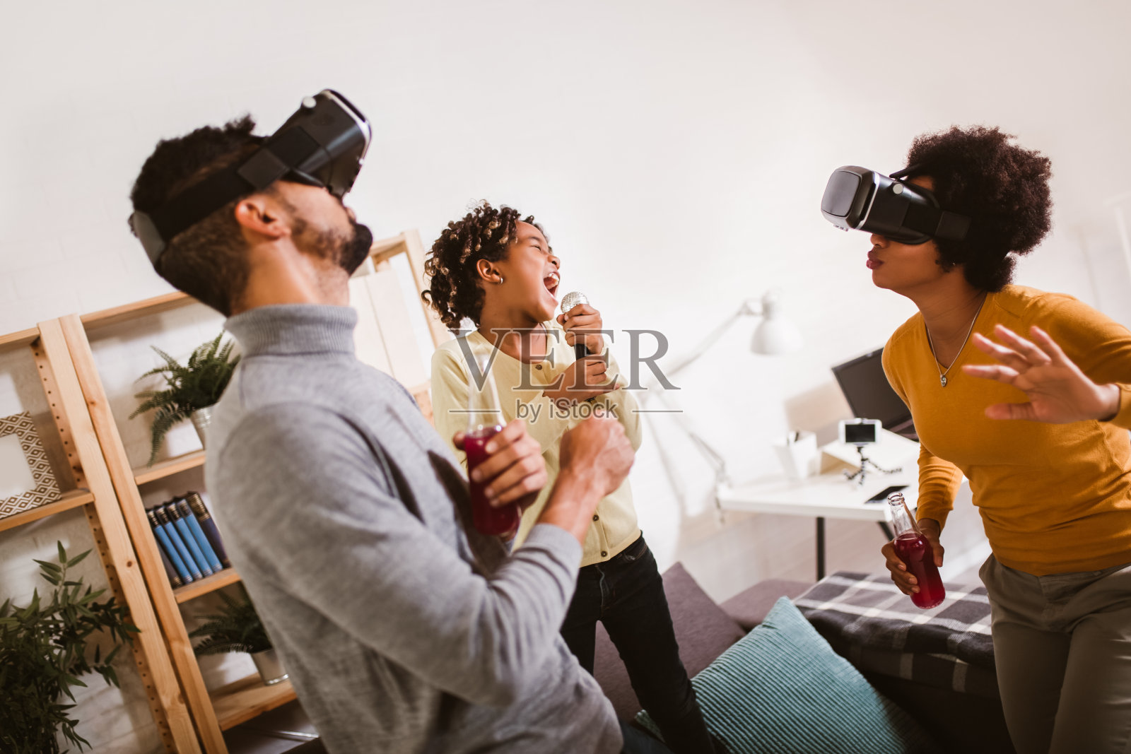 快乐的黑人家庭在家。爸爸，妈妈和女儿在玩虚拟现实。照片摄影图片