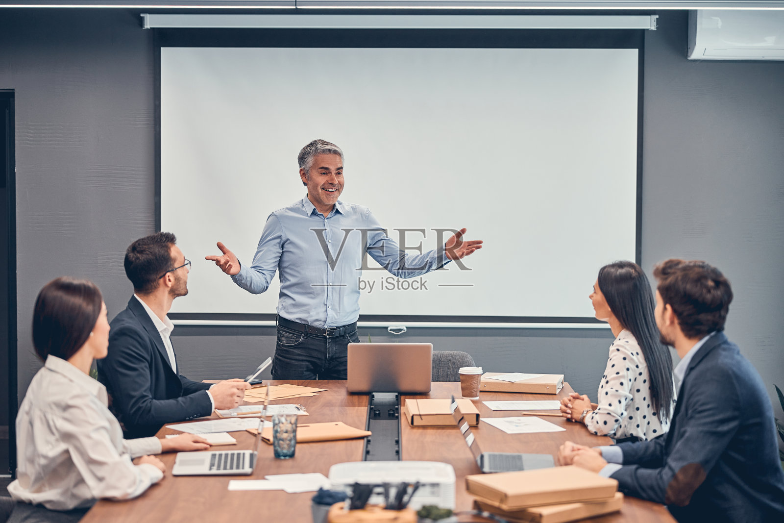 成年商人在会议上欢迎他的团队照片摄影图片