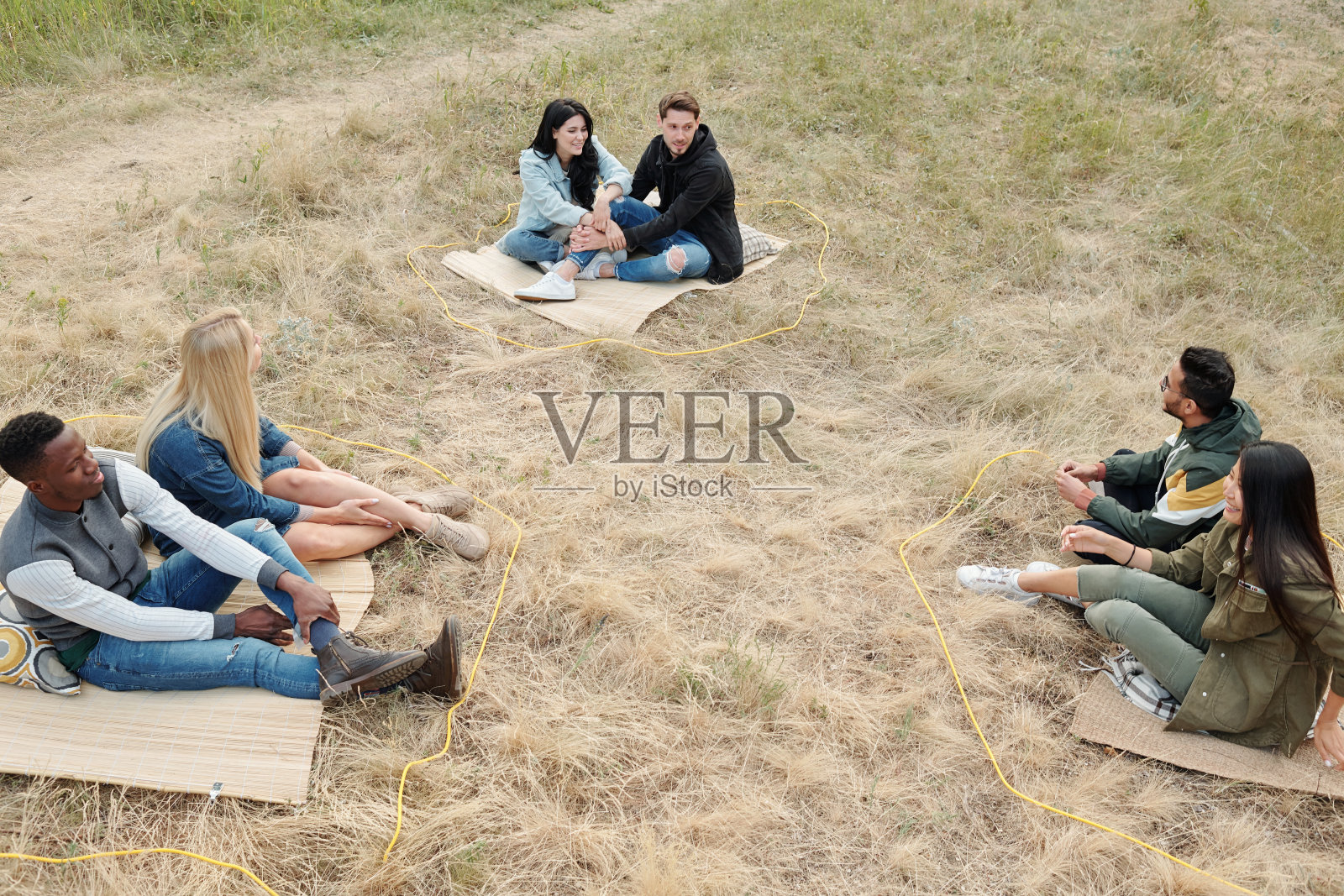 三对跨文化夫妇坐在干草上保持社交距离照片摄影图片