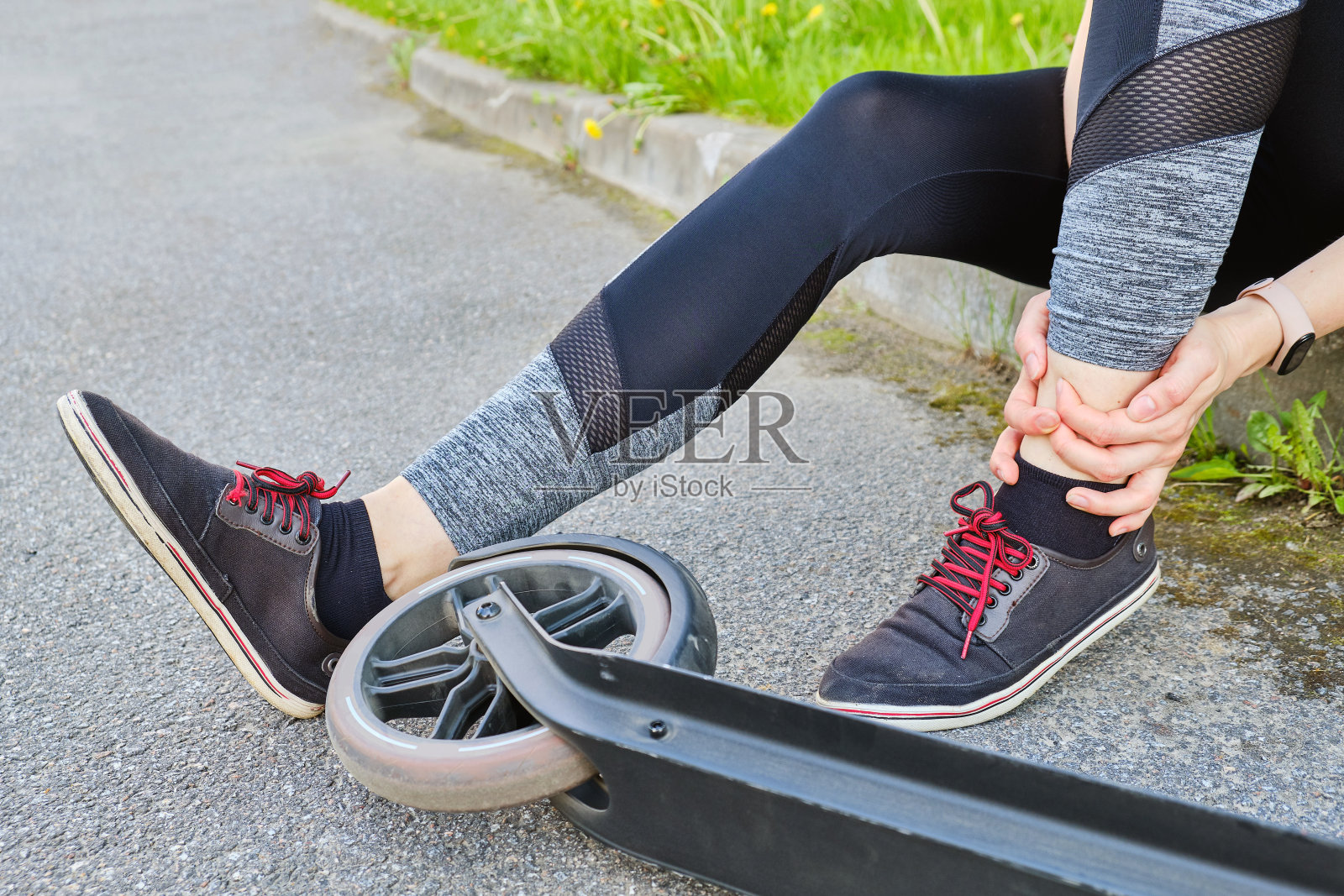 小女孩骑摩托车后腿部受伤，坐在地上。照片摄影图片