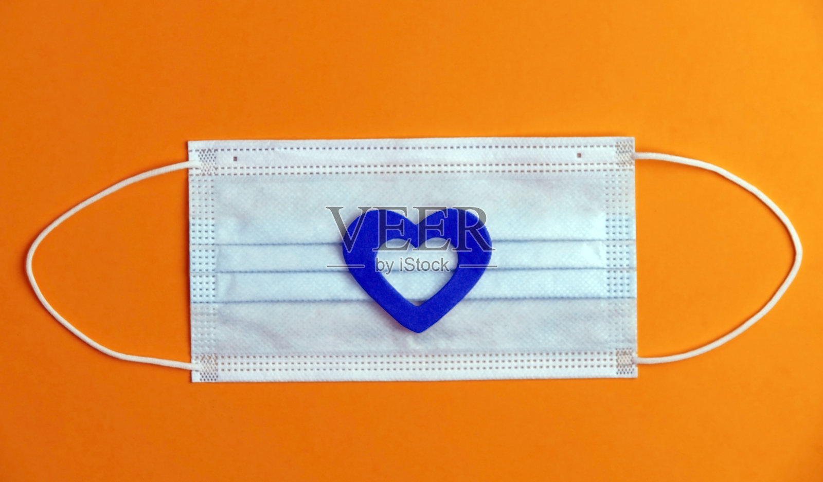 COVID-19概念，防毒面具，蓝心，橙色背景，文字空间。俯视图照片摄影图片
