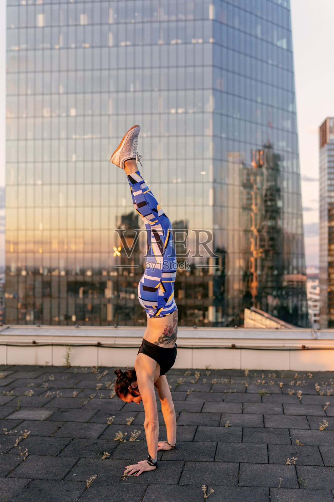 年轻女人在屋顶上倒立，享受自由和日落照片摄影图片