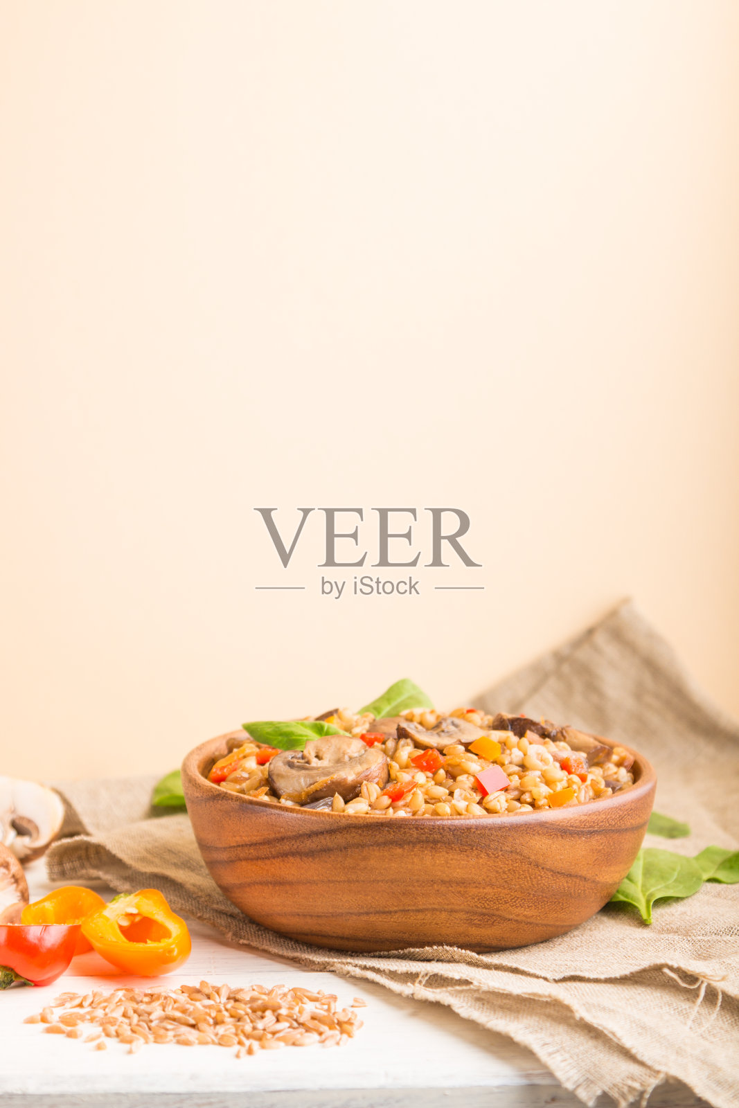 斯匹尔特小麦粥与蔬菜和蘑菇木碗在白色和橙色的背景和亚麻纺织品。侧视图，选择性聚焦，复制空间。照片摄影图片