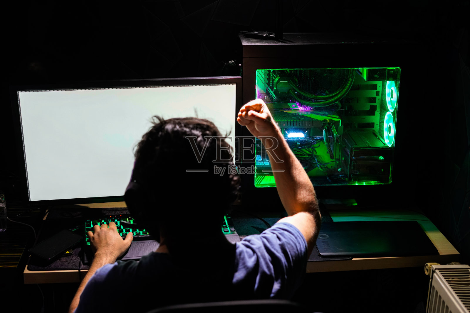 玩家男在绿色高端电脑上庆祝赢得电子竞技比赛照片摄影图片