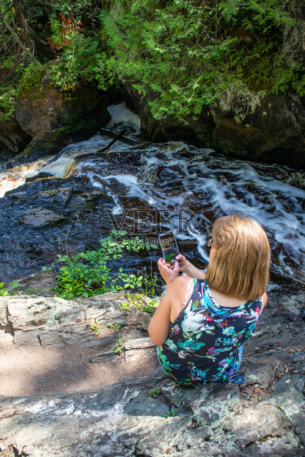 一位女士正在用她的智能手机给一条河拍照照片摄影图片