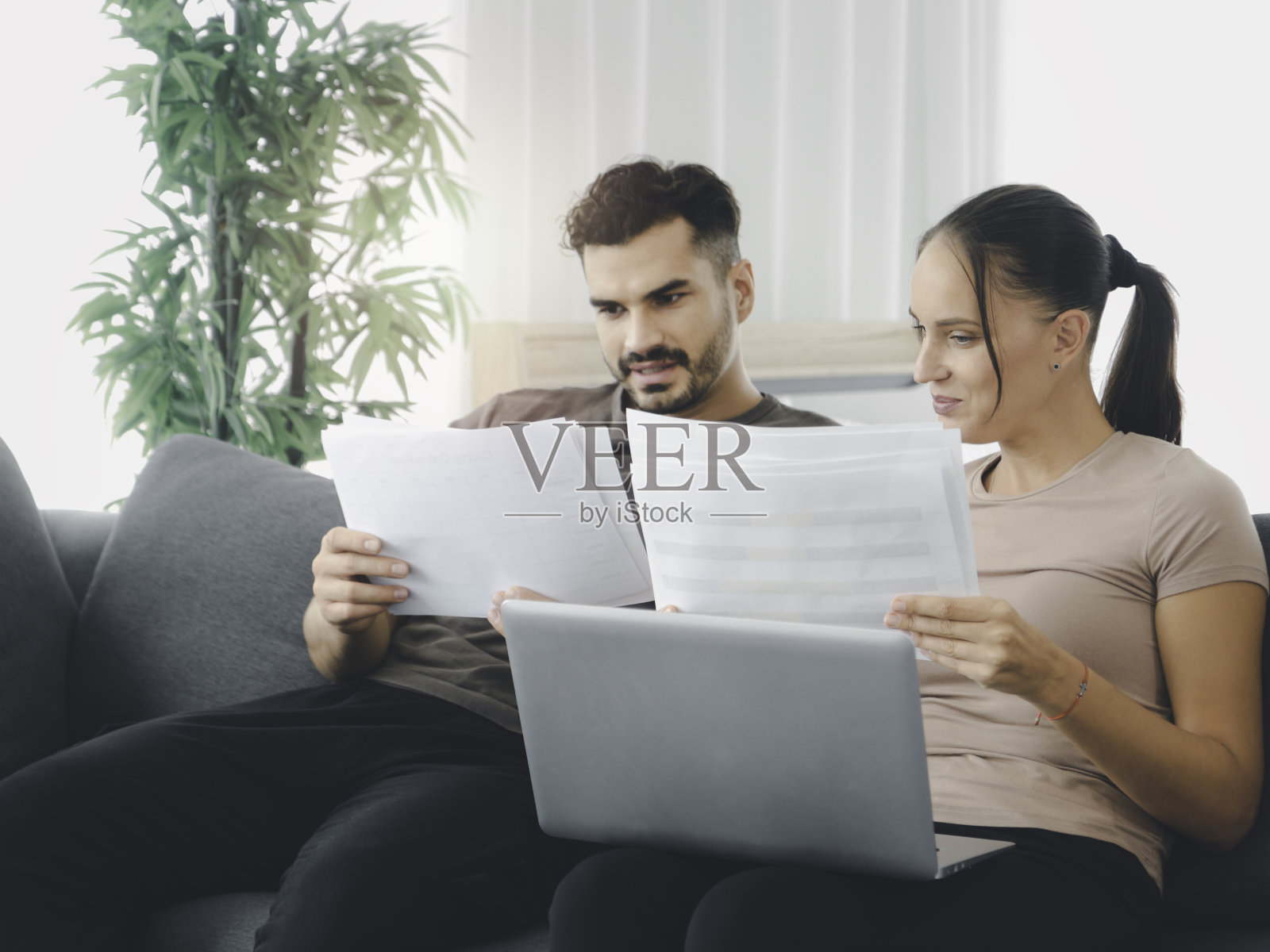 夫妻在家里用笔记本电脑和纸质文件工作，在网上搜索信息和购物，年轻人使用社交媒体在线商务会议，新的常态工作形式的家庭概念照片摄影图片