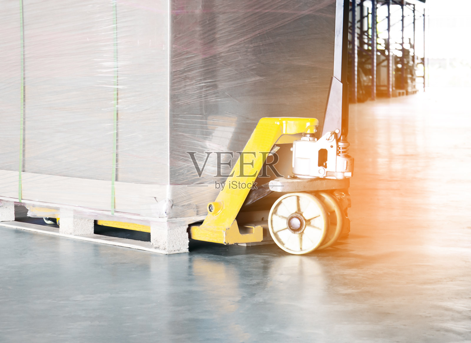 手动托盘搬运车与装运托盘货物在仓库储存。照片摄影图片