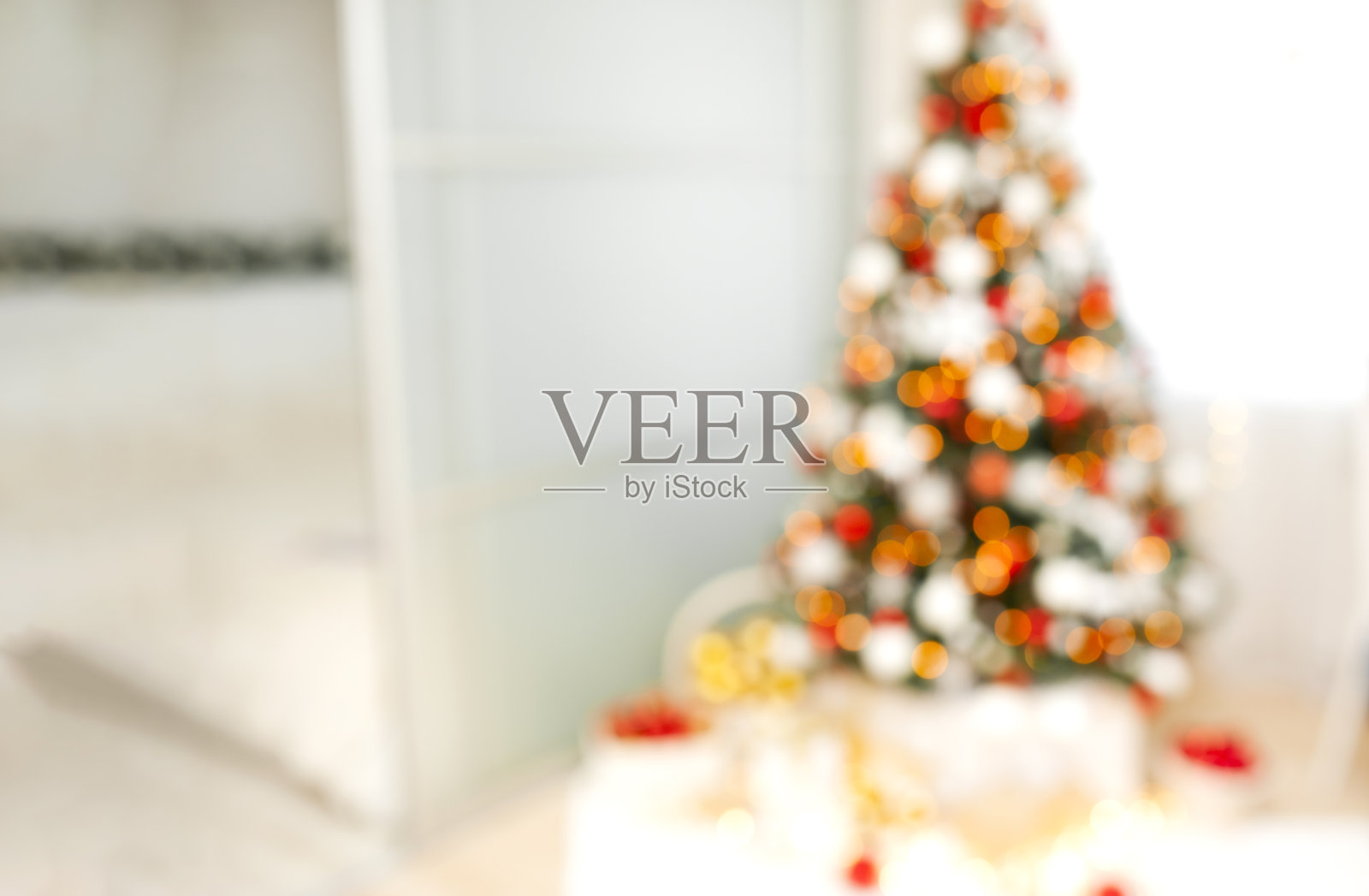 在明亮的房间里，橙色、黄色和红色的灯光使圣诞树失去了焦点。假日背景与文字空间照片摄影图片