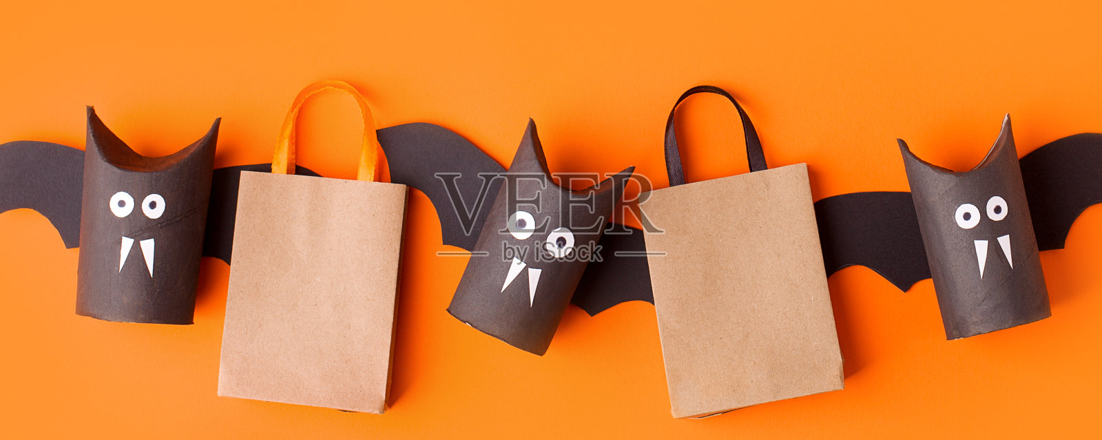 秋季万圣节假日销售概念-玩具从厕纸卷管，回收的想法和纸工艺购物袋在橙色的背景，环保容易diy，传单，优惠券照片摄影图片