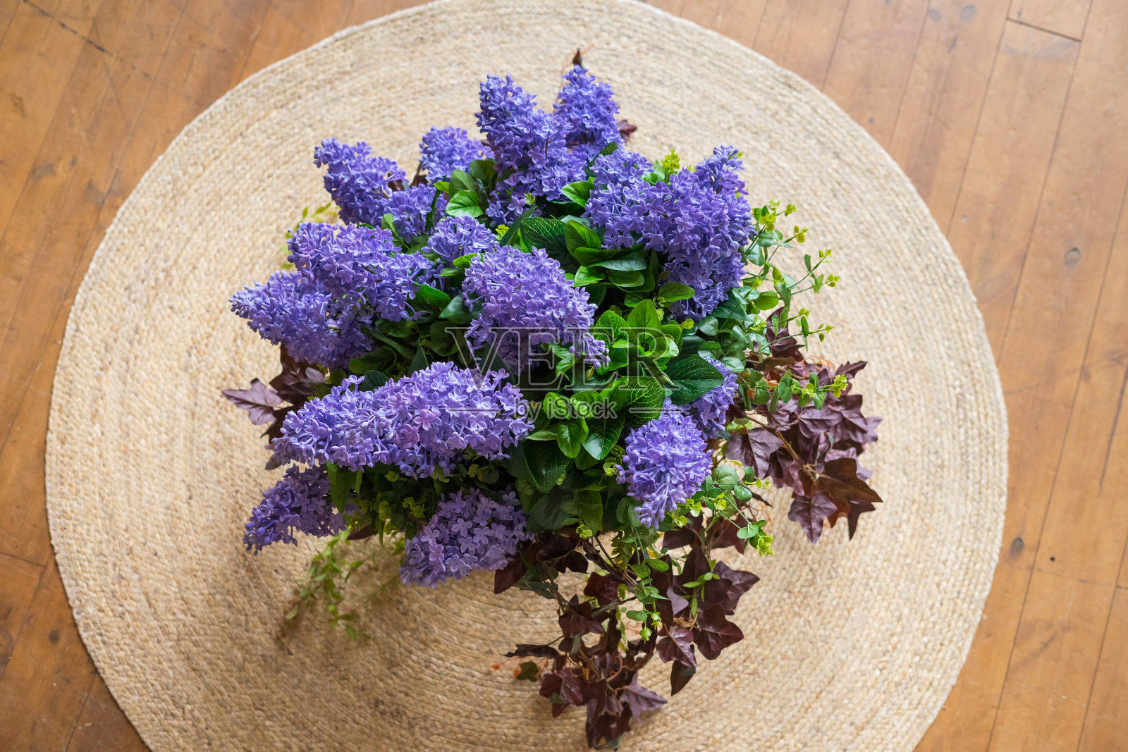 一张圆形柳条地毯上挂着一大堆紫丁香。前视图。照片摄影图片