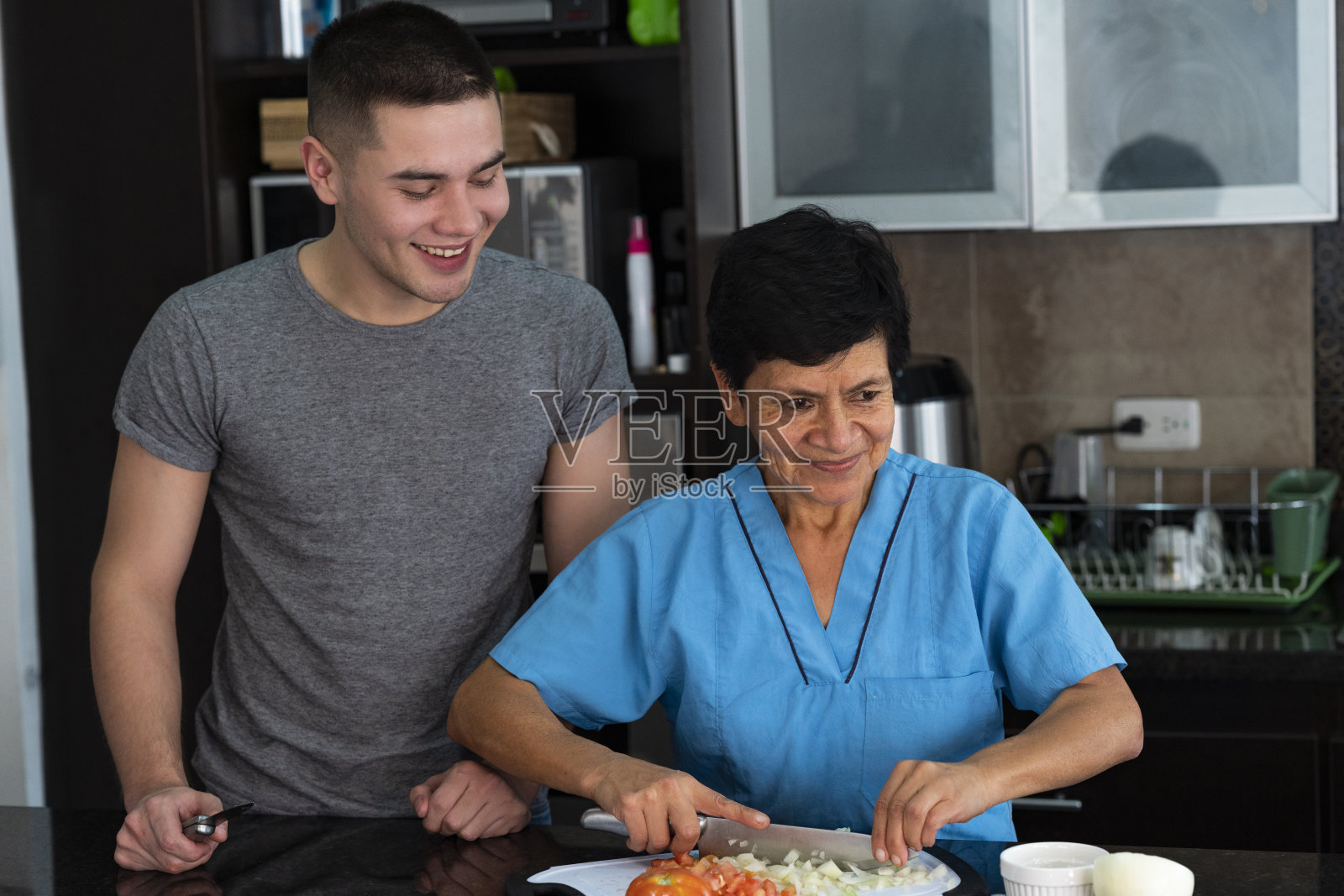 年轻男子接受烹饪课程从她的家庭助手从她的家庭厨房照片摄影图片