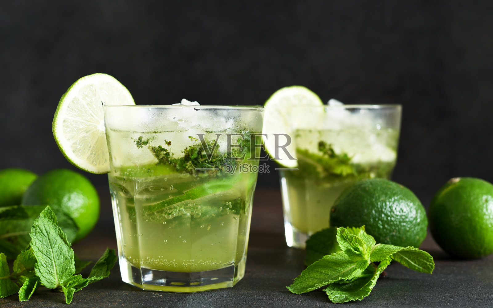 夏季鸡尾酒。经典的夏季饮料-莫吉托在一个玻璃杯在一个黑暗的背景。照片摄影图片