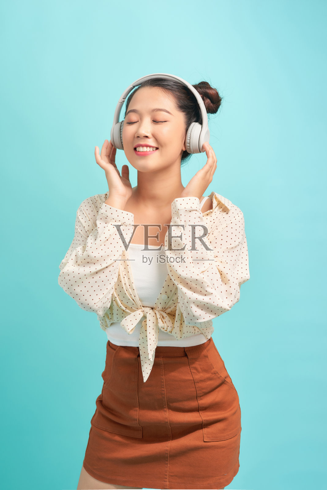 迷人的女孩，穿着短裤，戴着耳机，舞动着头发，闭着眼睛。照片摄影图片