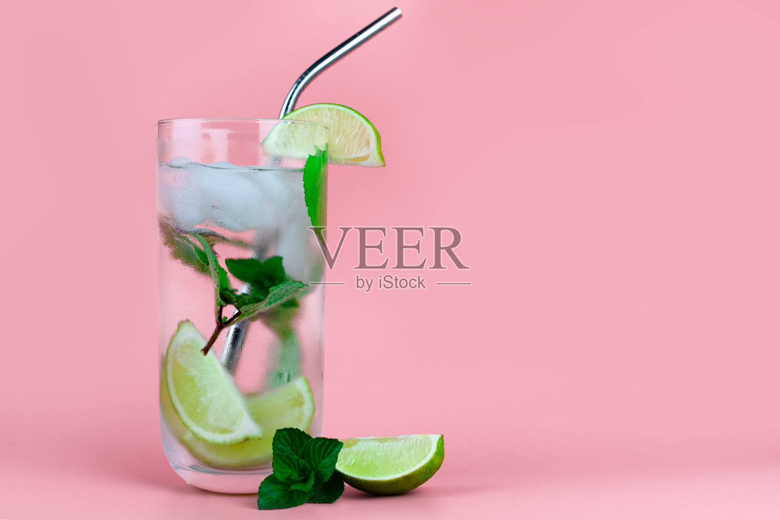 含鸡尾酒或不含酒精的莫吉托，配上新鲜的薄荷和酸橙，粉色背景上的人们用环保吸管。文本。照片摄影图片