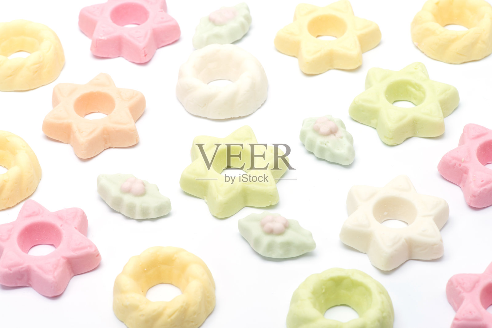 多种颜色的绿色/橙色/白色和粉红色的圣诞糖果躺在一个图案，冬青叶，星星，糖果花环照片摄影图片