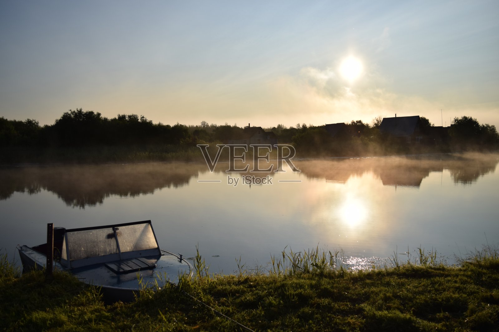 有一条河和冉冉升起的太阳。靠近岸边的一条船。清晨照片摄影图片