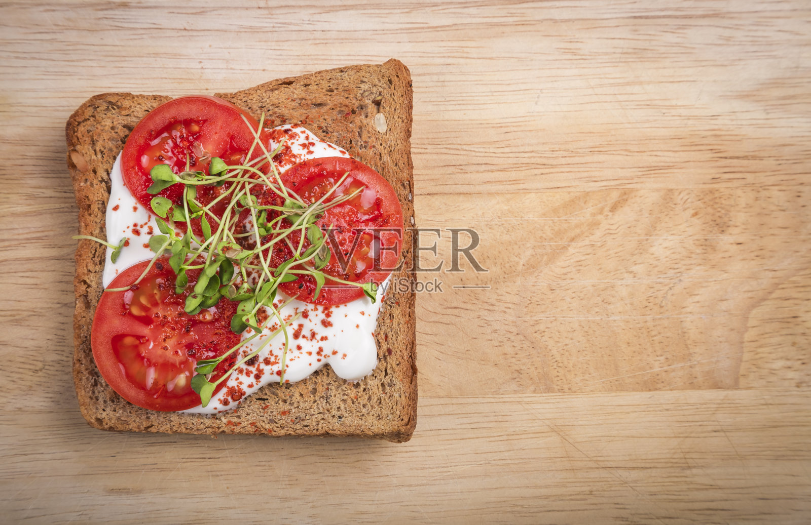 在切菜板上加入奶油芝士、蔬菜、番茄片和香料的健康三明治。健康饮食，饮食素食。前视图。照片摄影图片