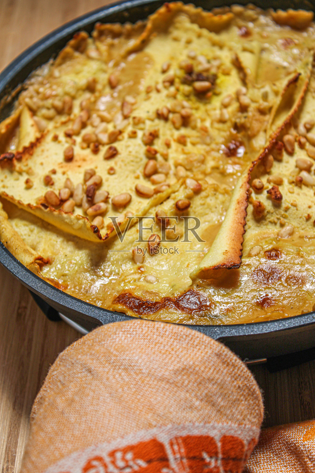 白色素食千层面上面有松子和韭菜。照片摄影图片