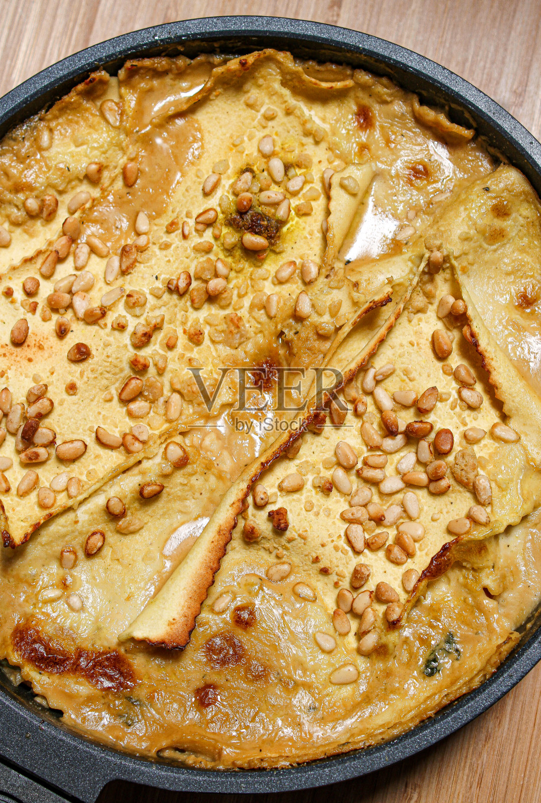 白色素食千层面上面有松子和韭菜。照片摄影图片